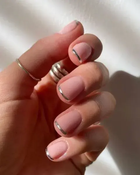 Un diseño de uñas bien cortas, con manicura francesa pero reemplazando el esmalte blanco por uno plateado. Clásicas pero con toque distinto. Un diseño de uñas bien cortas, con manicura francesa pero reemplazando el esmalte blanco por uno plateado. Clásicas pero con toque distinto.