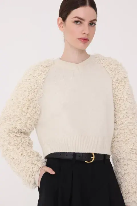 Este sweater de lana merino tiene flecos en las mangas, elaborados de manera artesanal. @thecream.arg