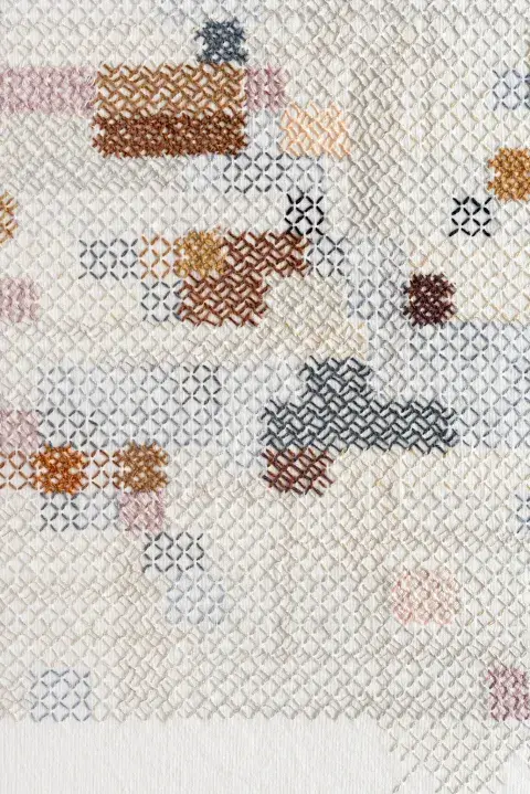 Al acercarse al textil, se ve el trabajo de bordado compuesto por diferentes patrones y secuencias Al acercarse al textil, se ve el trabajo de bordado compuesto por diferentes patrones y secuencias