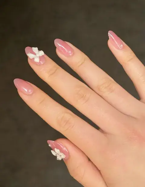 Los tonos rosados pastel con apliques de moños blancos en una sola uña queda elegante y remite también al estilo Coquette. Los tonos rosados pastel con apliques de moños blancos en una sola uña queda elegante y remite también al estilo Coquette.
