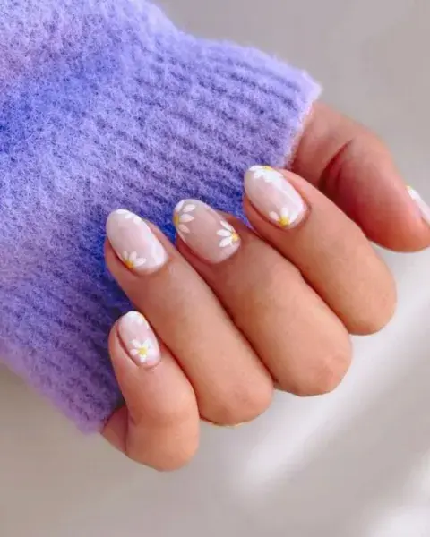Foto de una mano de mujer con nail art de margaritas.