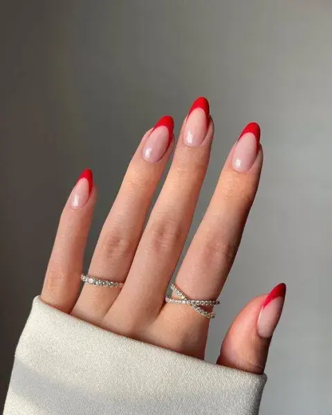 Una mano con un diseño de uñas francesita pero hechas en color rojo Una mano con un diseño de uñas francesita pero hechas en color rojo