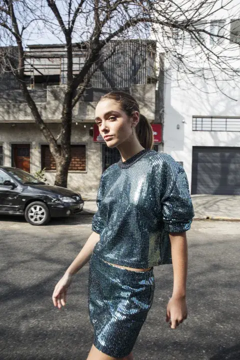 Una mujer caminando con una blusa y una pollera brillante Una mujer caminando con una blusa y una pollera brillante