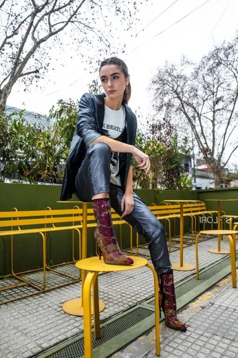 Una mujer posando en un banco de plaza con un look de brillos Una mujer posando en un banco de plaza con un look de brillos