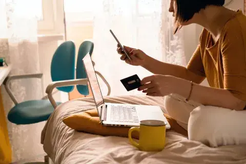 Mujer comprando online con una tarjeta de crédito en la mano Mujer comprando online con una tarjeta de crédito en la mano