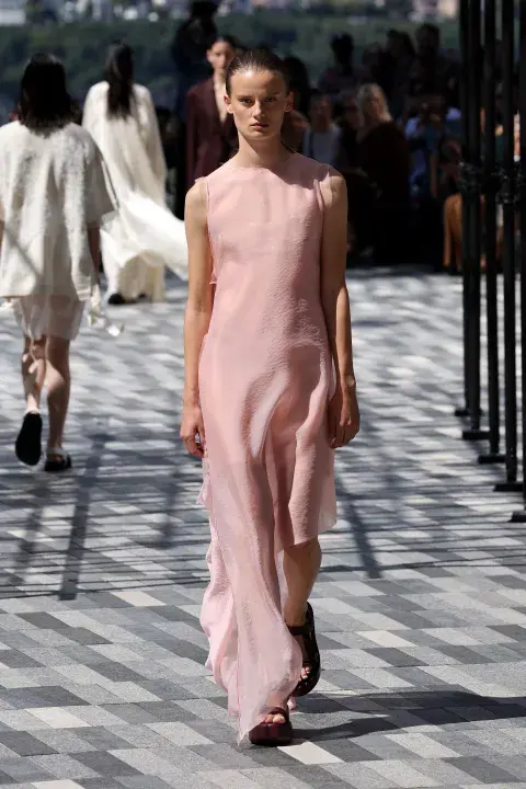 Una mujer caminando por la pasarela vestida de color rosa claro Una mujer caminando por la pasarela vestida de color rosa claro