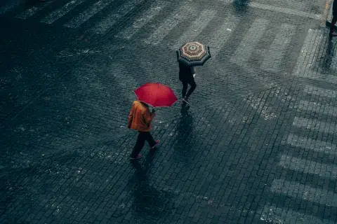 Dos personas debajo de la lluvia caminando con paraguas Dos personas debajo de la lluvia caminando con paraguas