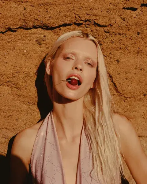 Una modelo mostrando una cereza entre sus labios. Una modelo mostrando una cereza entre sus labios.