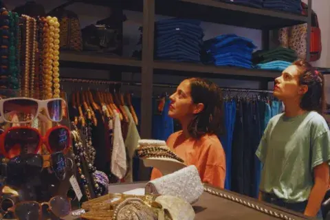 Dos mujeres miran percheros de ropa. Dos mujeres miran percheros de ropa.