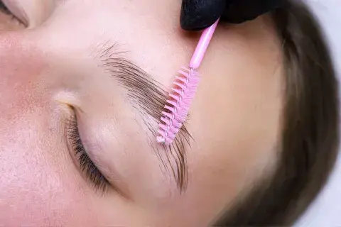 Una mujer peinándose las cejas con un cepillo Una mujer peinándose las cejas con un cepillo