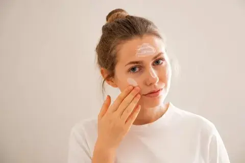 Una mujer poniéndose crema en el rostro Una mujer poniéndose crema en el rostro