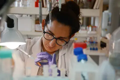 Una bióloga analizando células a través del microscopio Una bióloga analizando células a través del microscopio