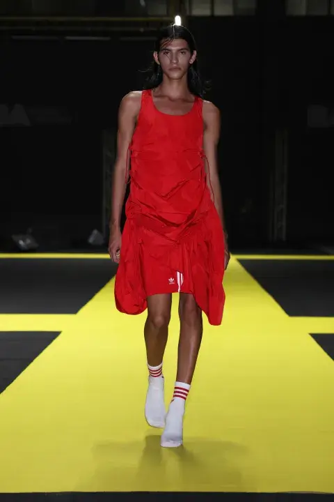 Un modelo caminando por la pasarela de Designes con un atuendo en color rojo Un modelo caminando por la pasarela de Designes con un atuendo en color rojo
