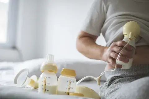 Una mujer extrayendo leche materna con un sacaleche Una mujer extrayendo leche materna con un sacaleche