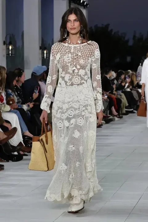 Una mujer caminando por una pasarela con un vestido de encaje en color blanco Una mujer caminando por una pasarela con un vestido de encaje en color blanco
