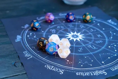La rueda zodiacal, con los símbolos de los 12 signos astrales y encima unos dados astrológicos. La rueda zodiacal, con los símbolos de los 12 signos astrales y encima unos dados astrológicos.