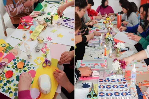 Papeles de colores sobre una mesa de trabajo y mujeres haciendo un taller craft.