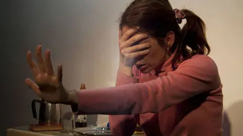 Una mujer tapándose la cara con la mano. Una mujer tapándose la cara con la mano.