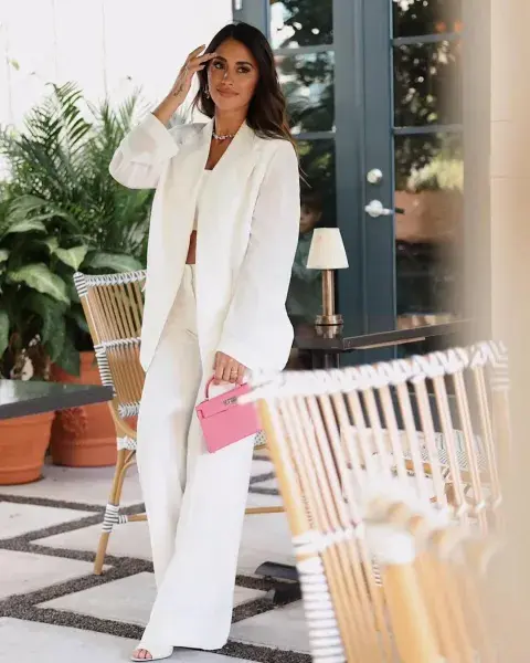 Antonela roccuzzo posando con un look sastrero total white y una cartera rosa Antonela roccuzzo posando con un look sastrero total white y una cartera rosa