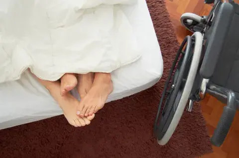 Pareja en la cama, una silla de ruedas al lado. Pareja en la cama, una silla de ruedas al lado.