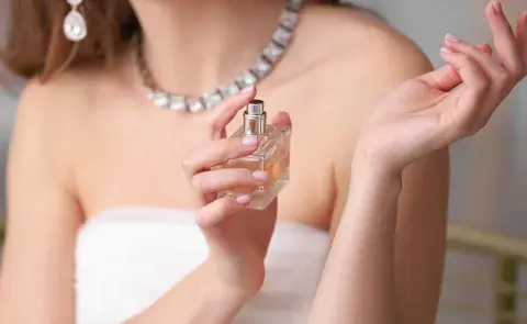 Una mujer aplicándose perfume en la muñeca Una mujer aplicándose perfume en la muñeca