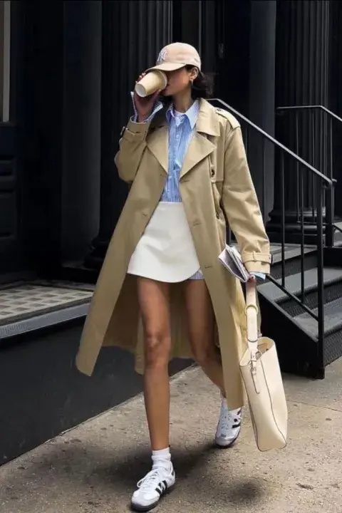 Una mujer usando un trench y zapatillas deportivas Una mujer usando un trench y zapatillas deportivas