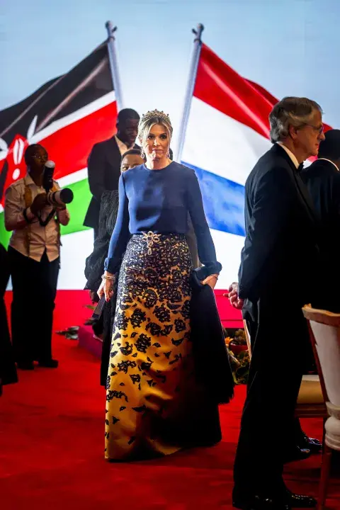 Para un banquete en Kenia, Máxima optó por una blusa azul de manga larga y falda dorada con estampado floral. Para un banquete en Kenia, Máxima optó por una blusa azul de manga larga y falda dorada con estampado floral.
