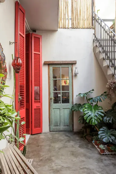 Los postigones rojos acentúan los tonos sobrios de este típico patio de entrada y distribución de un PH en Flores. Los postigones rojos acentúan los tonos sobrios de este típico patio de entrada y distribución de un PH en Flores.