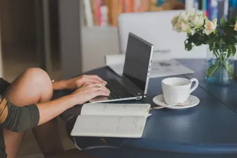 Una mujer escribiendo en una computadora.