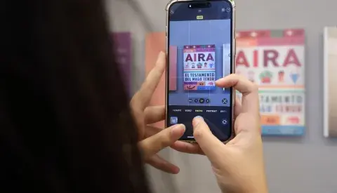 Un celular sacando una foto a un cartel con el nombre de Aira