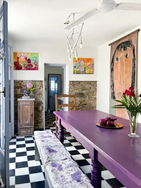 En el comedor, una mesa de trabajo comprada en un remate, pintada de violeta intenso por la artista. Un gran cuadro de Celia Basavilbaso se combinó con dos de Goñi. 