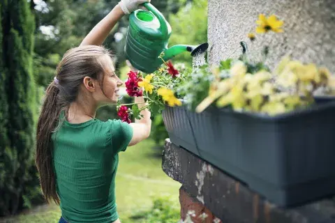 Foto de mujer regando las plantas.