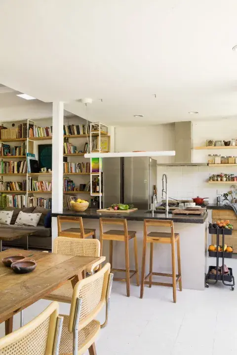 Muebles de cocina (Estudio YME) y estantes de guatambú amurados. Sobre la isla, luminaria lineal (iMdi Iluminación). Banquetas (Enecueros). Muebles de cocina (Estudio YME) y estantes de guatambú amurados. Sobre la isla, luminaria lineal (iMdi Iluminación). Banquetas (Enecueros).