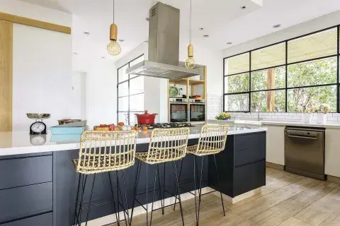 Isla central laqueada (HPS Design, Fabián Portal) con anafe y mesada de Silestone en ‘WhiteStorm’. Banquetas de mimbre (Brugués Mosconi).