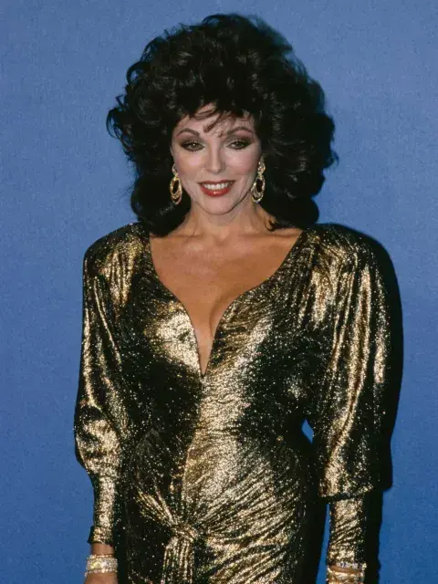 Joan Collins, 1986 Un clásico de los ’80: vestido dorado con hombreras marcadas (“shoulder pads”) y escote tipo corazón. Joan Collins, 1986 Un clásico de los ’80: vestido dorado con hombreras marcadas (“shoulder pads”) y escote tipo corazón.