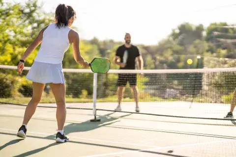 Una cancha de pickeball y dos personas jugando.