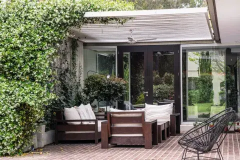 La galería con piso de adoquines de madera alberga un living con sillones cómodos para disfrutar del aroma del jazmín que crece por el muro y trepa por la pérgola. La galería con piso de adoquines de madera alberga un living con sillones cómodos para disfrutar del aroma del jazmín que crece por el muro y trepa por la pérgola.