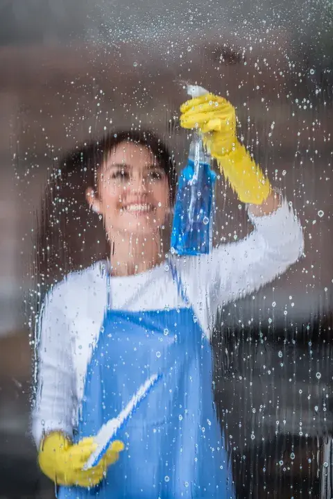 Foto de mujer limpiando ventanas.