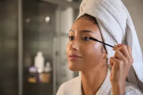 Foto de mujer peinandose las pestañas.
