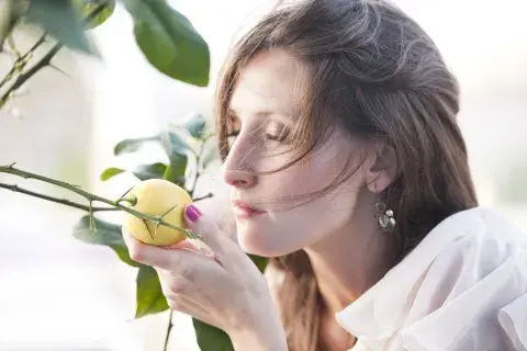 Foto de mujer oliendo un limón.
