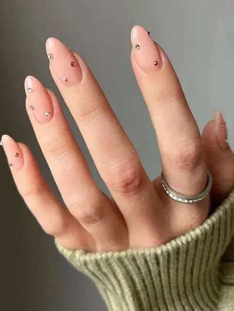 Las bases nude se actualizan con un detalle inesperado: un mini strass, una línea dorada o un punto de color.
