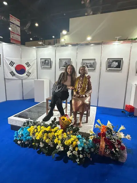 Pilar en el Stand de Corea, con una escultura que representa a las abuelas revolucionarias que investigó. Pilar en el Stand de Corea, con una escultura que representa a las abuelas revolucionarias que investigó.