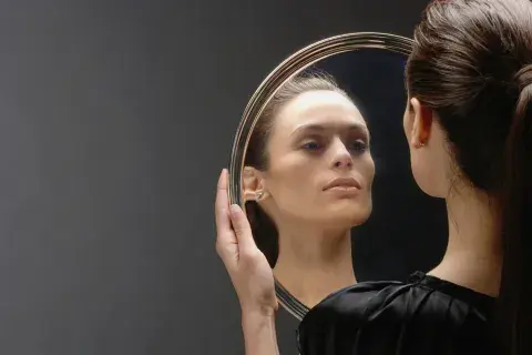 Foto de mujer mirándose en un espejo.
