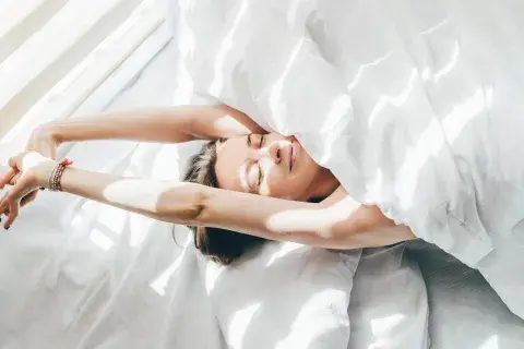 Foto de mujer despertando en la cama.