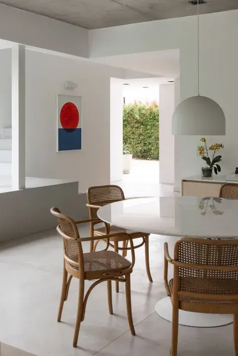 Una mesa de estilo ‘Tulip’ con tapa de mármol Calacatta y sillas ‘Thonet’. 