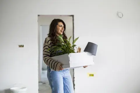 Foto de mujer llegando a su casa con una planta. Foto de mujer llegando a su casa con una planta.