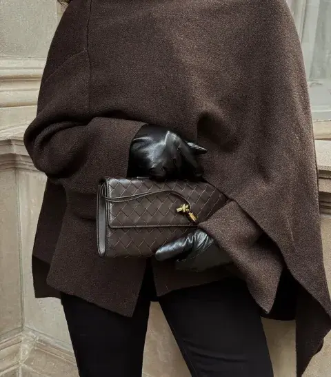 Una mujer con un poncho y guantes de cuero sosteniendo su cartera Una mujer con un poncho y guantes de cuero sosteniendo su cartera