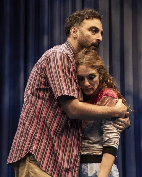 Un actor y una actriz sobre el escenario: ambos se abrazan con gesto triste. Un actor y una actriz sobre el escenario: ambos se abrazan con gesto triste.