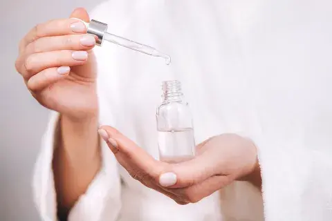 Una mujer con un frasco de serum en la mano