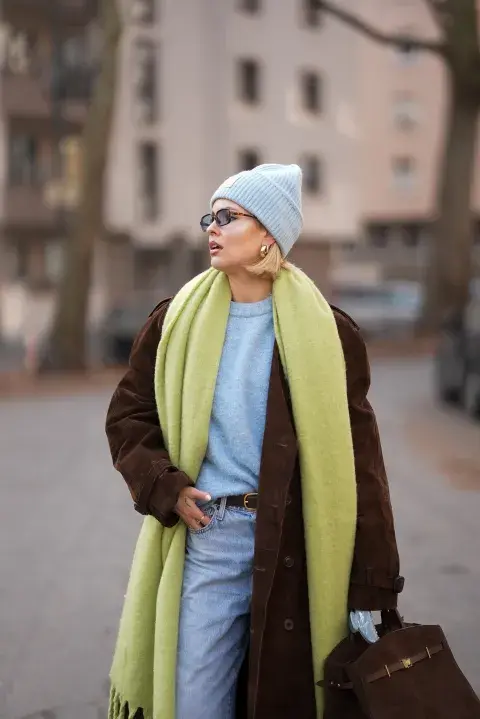 Una mujer usando una bufanda verde y un abrigo en color marrón Una mujer usando una bufanda verde y un abrigo en color marrón